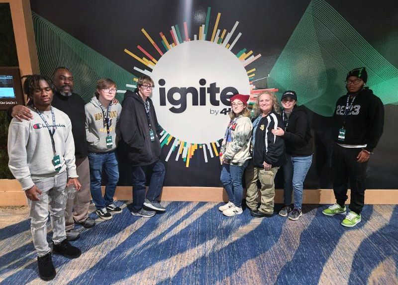 Group stands in front of ignite sign.
