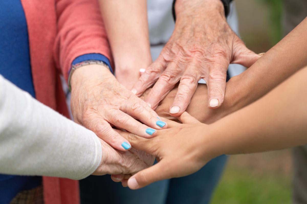 Concept of family aging society or teamwork hands showing unity with putting hands together senior wrinkled hands of old people together with other young people hands. High quality photo