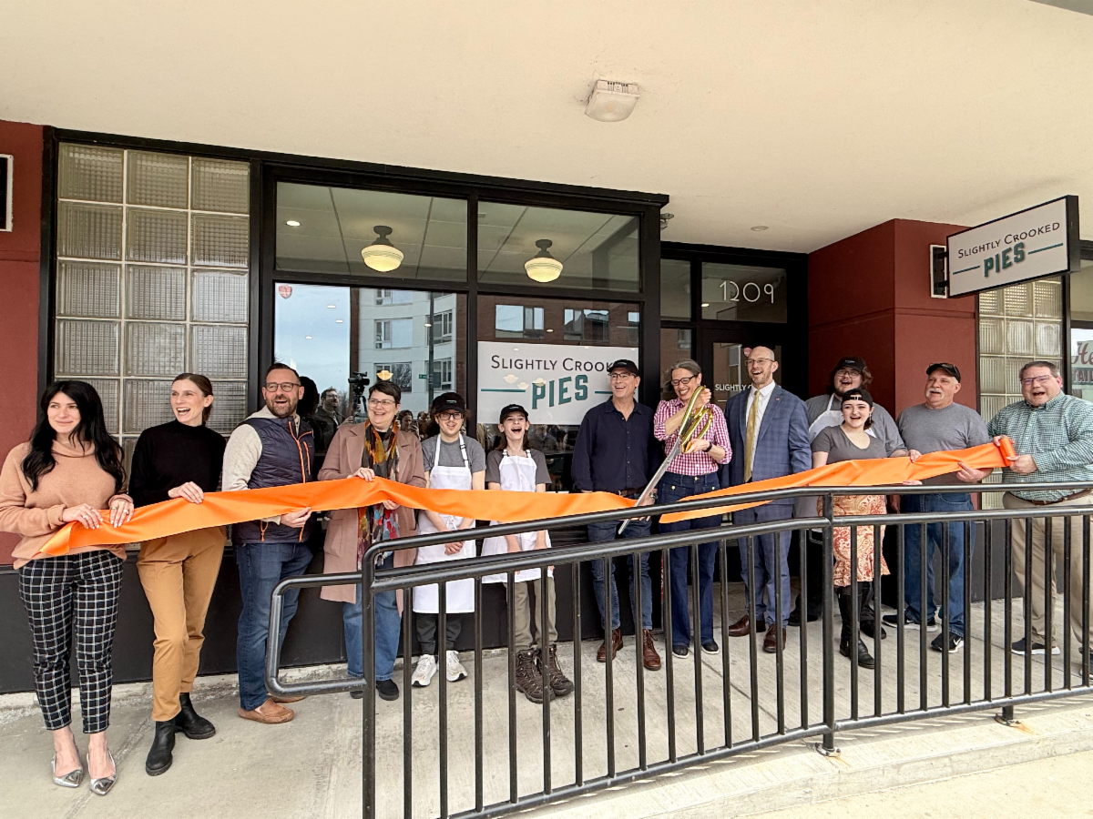 A group of individuals at a ribbon cutting for a new business grand opening