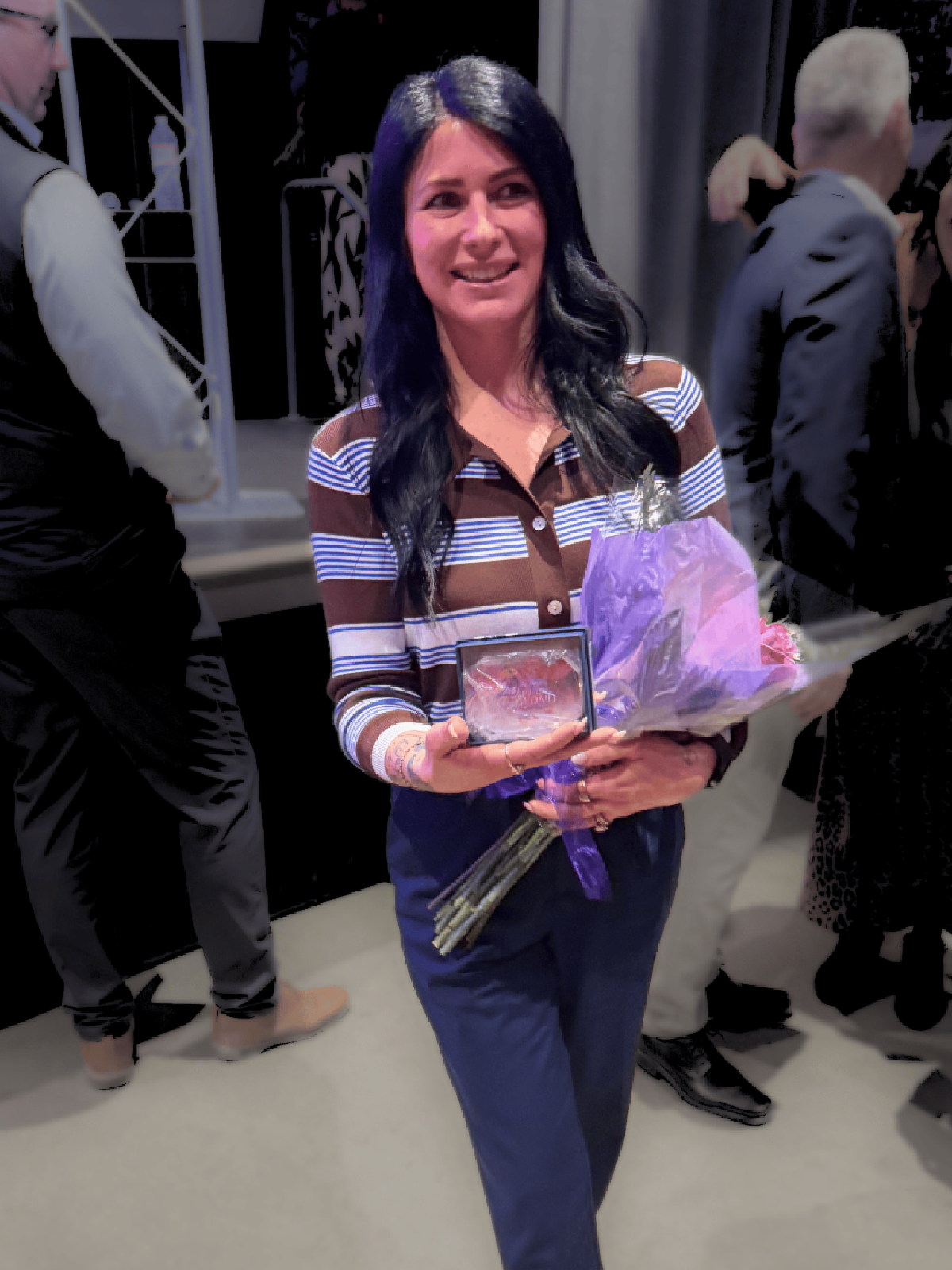 Jodie Nazaka with a bouquet of flowers and an award