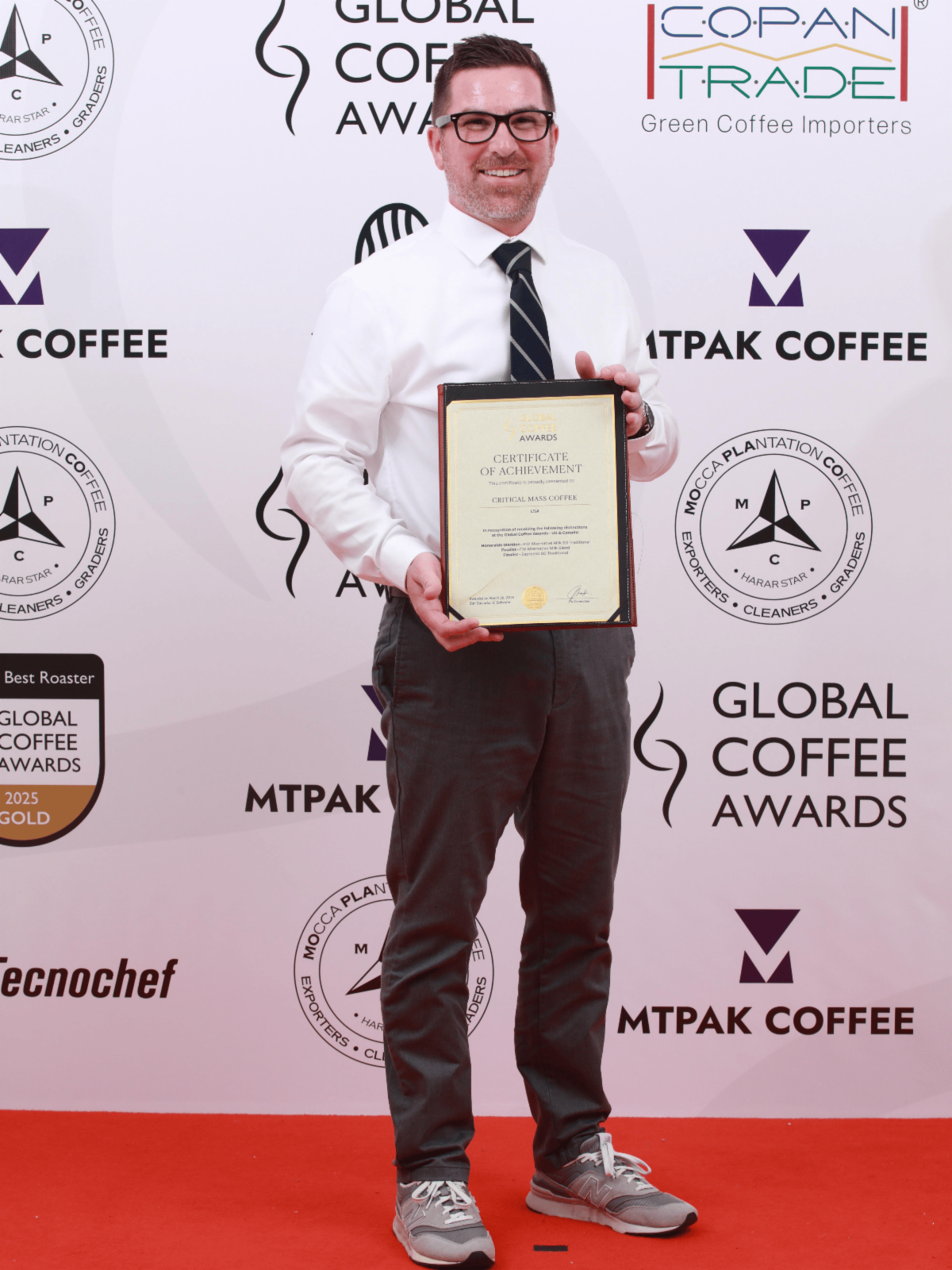 Ryan Connor holding a Certificate of Achievement from the Global Coffee Awards