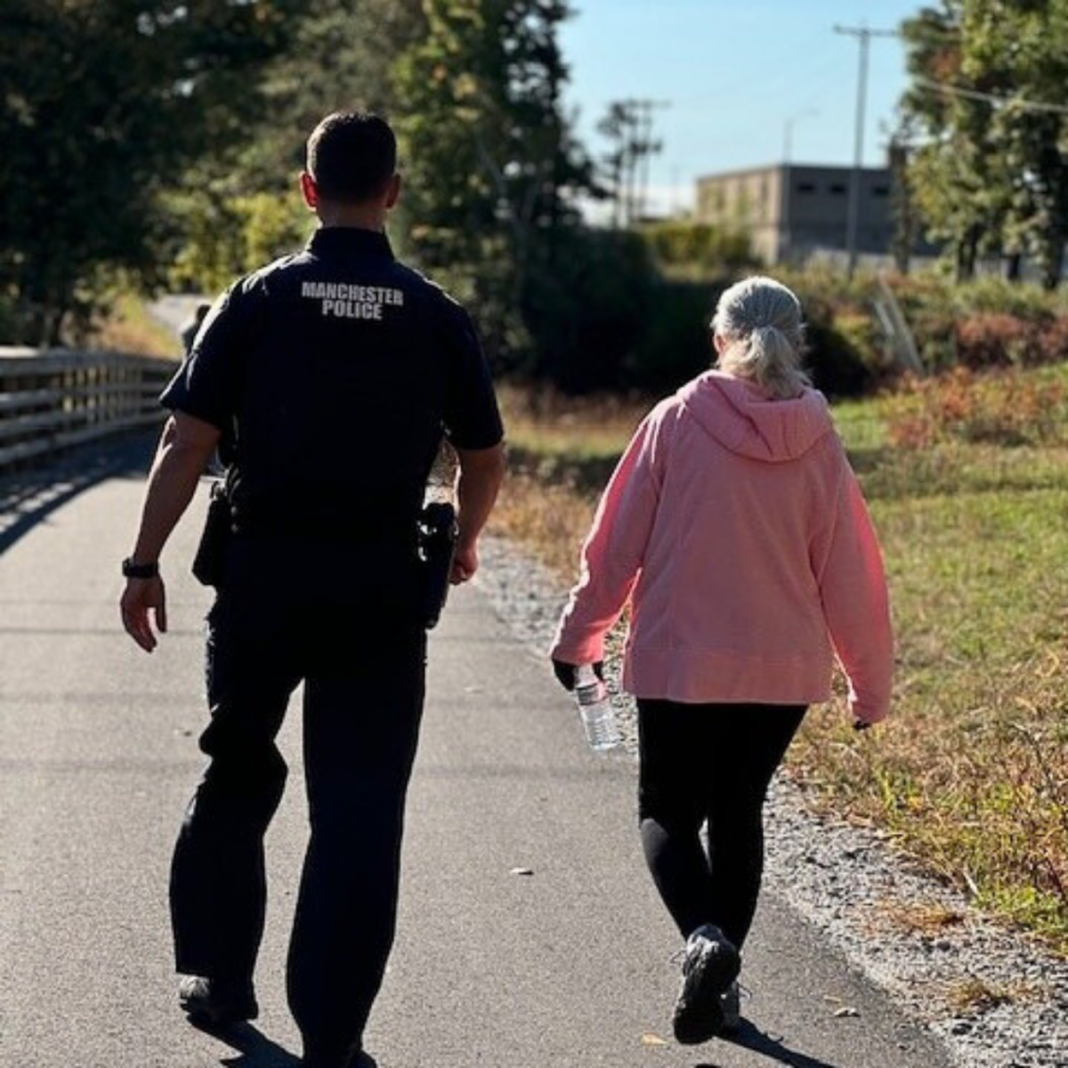 A senior walking with a Manchester Police officer during a planned outting