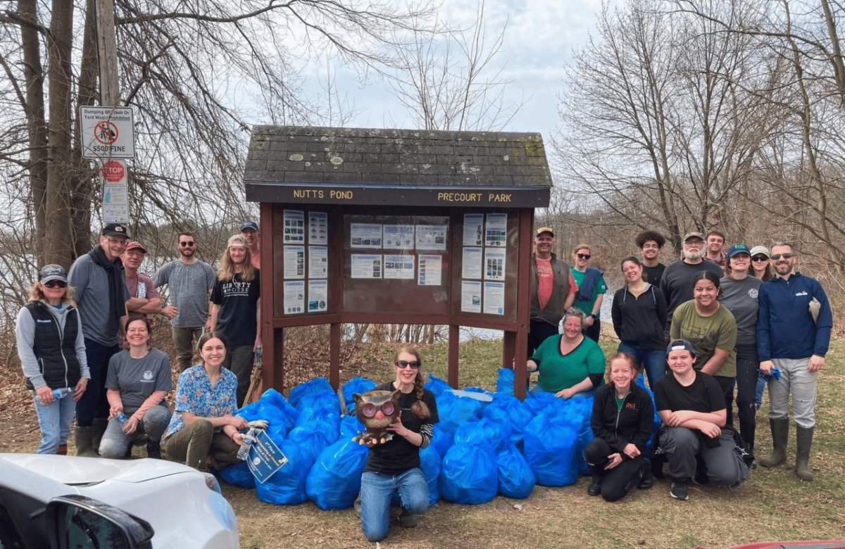 Group of individuals posing with blue bags filled with debris after cleaning up a City park