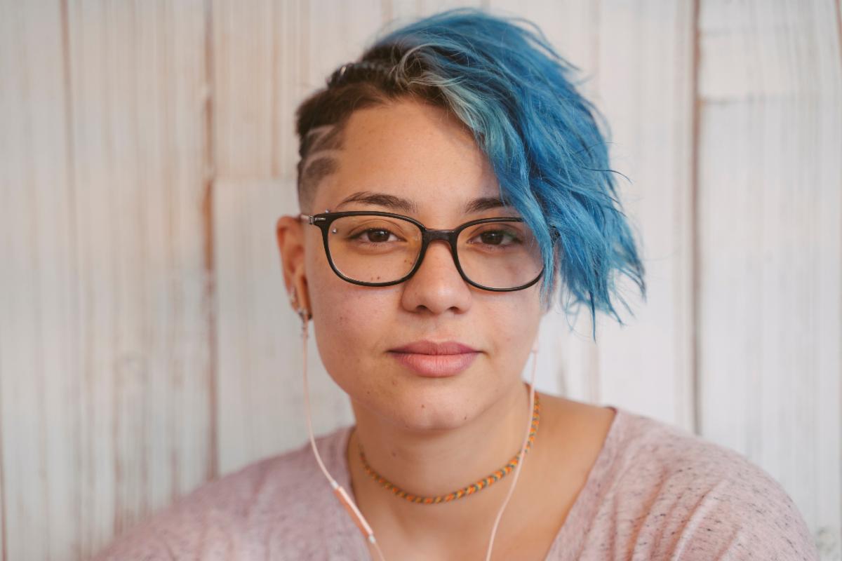portrait of a young woman with blue hair softly smiles
