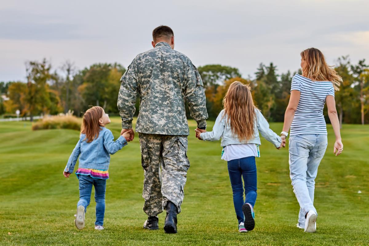 family walking. Soldier at vacation. Four family members walking together holding hands.