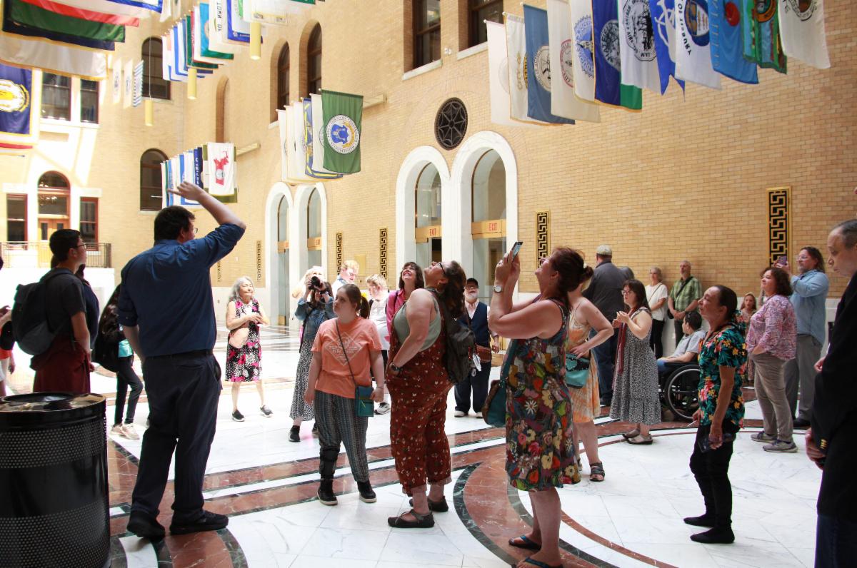 Boston State House tour of the flag room. A group of people look up at all the flags for each city and town of Massachusetts.