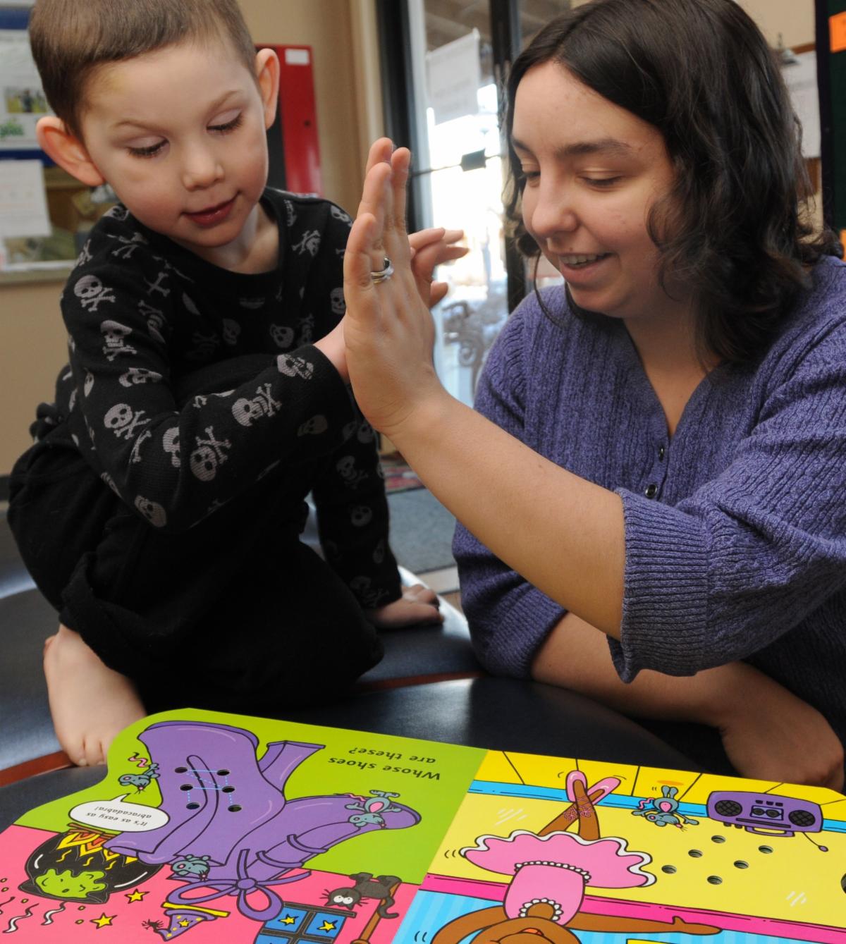 Whole Children program manager Amanda Kent with a young student reading a book