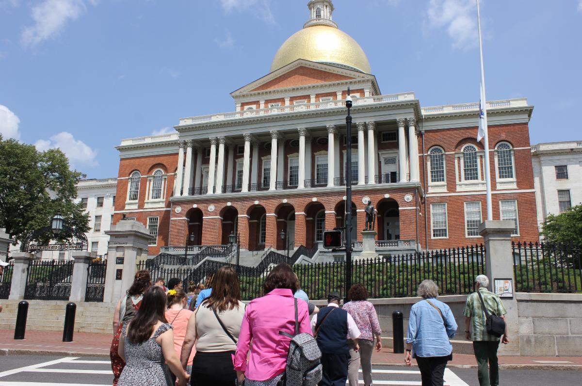 Pathlight supporters cross the street in front of the Boston State House building. The building has a giant gold dome.