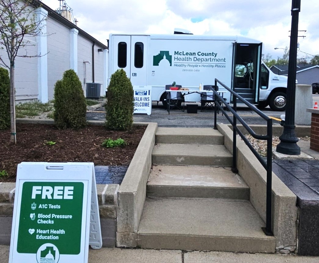 McLean County Health Dept Mobile Unit set up in Lexington with table and signs welcoming the public to free health screenings.