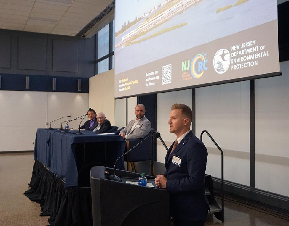 NJDEP Commissioner Shawn LaTourette speaking from podium as panelists look on.