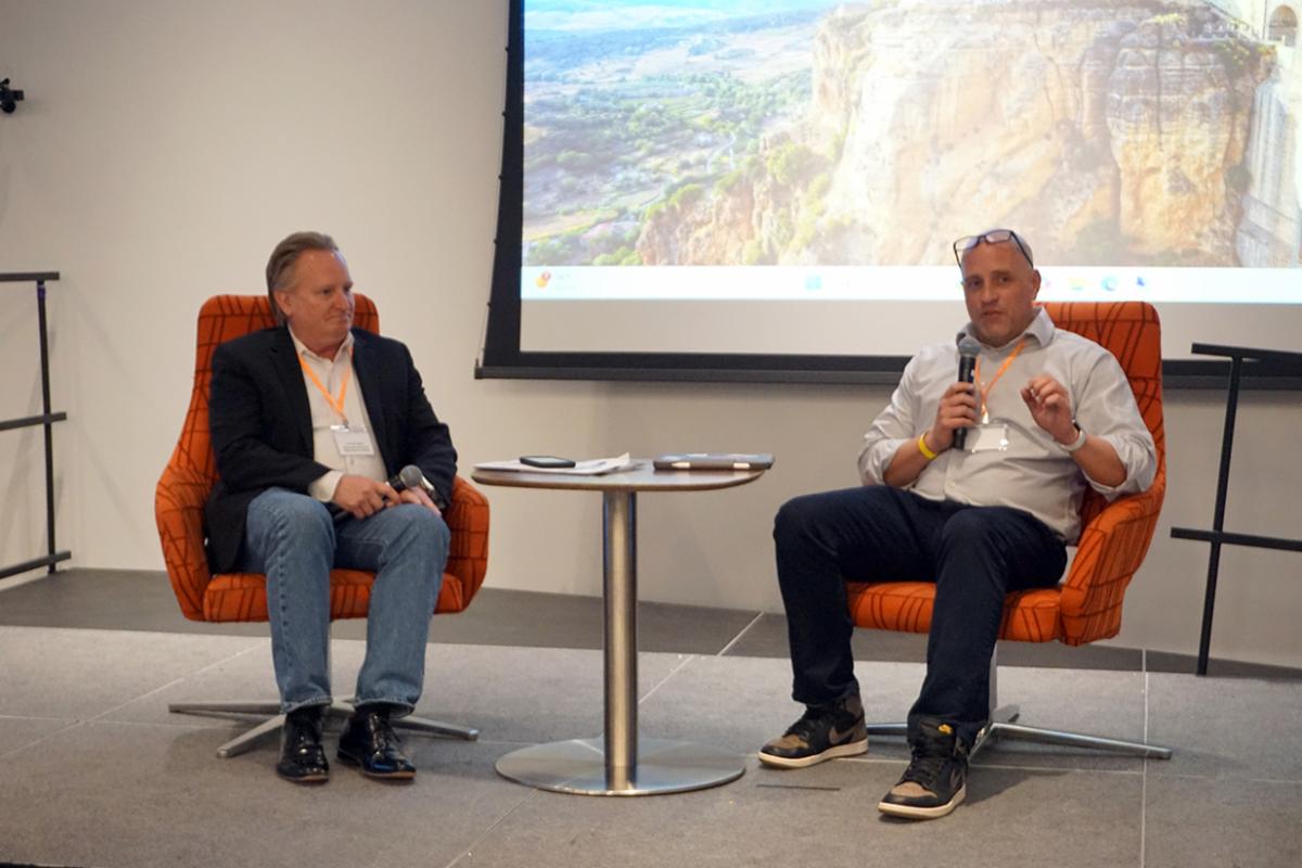 Two panel speakers seated on a stage