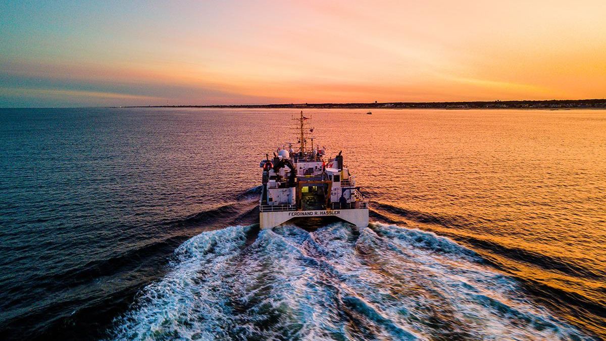 A NOAA exploration ship saling ahead at sunset