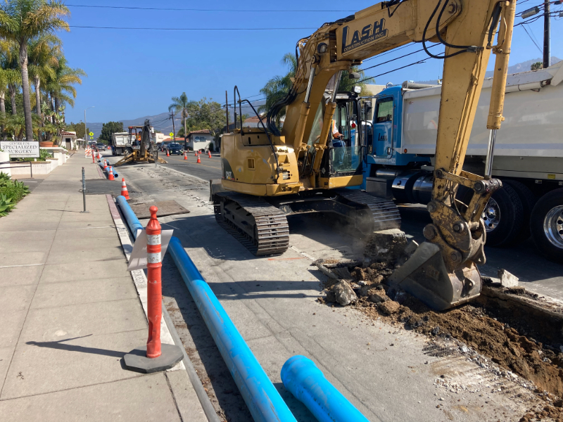 Heavy machinery digging up street for a water main replacement.