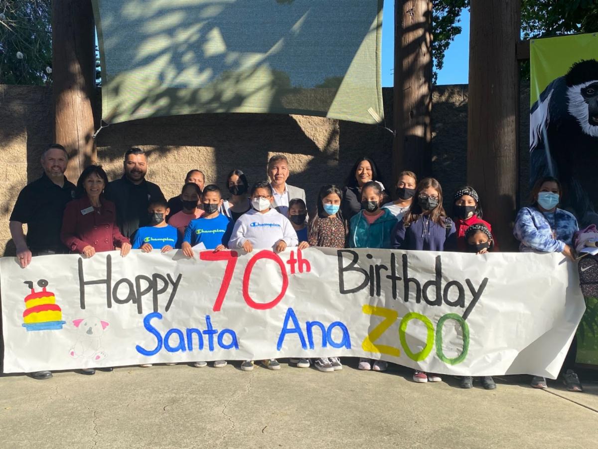 A picture of a group of people holding a banner that said Happy 70th birthday Santa Ana zoo