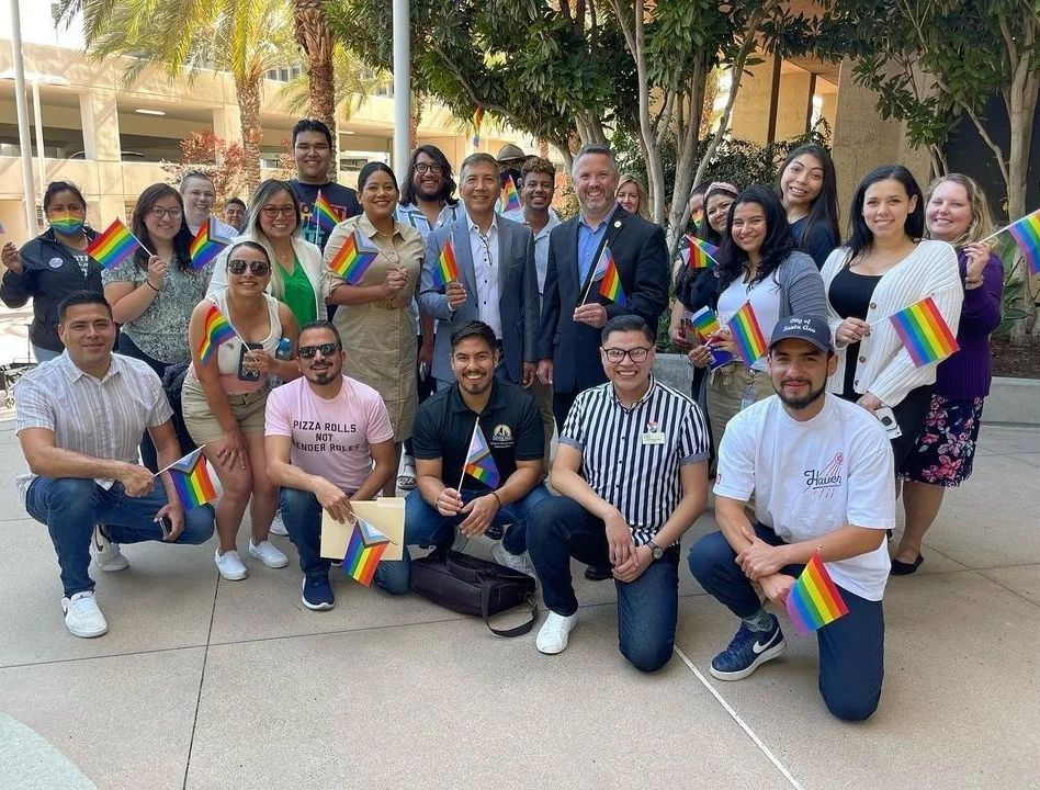 A group of people holding rainbow color flags.