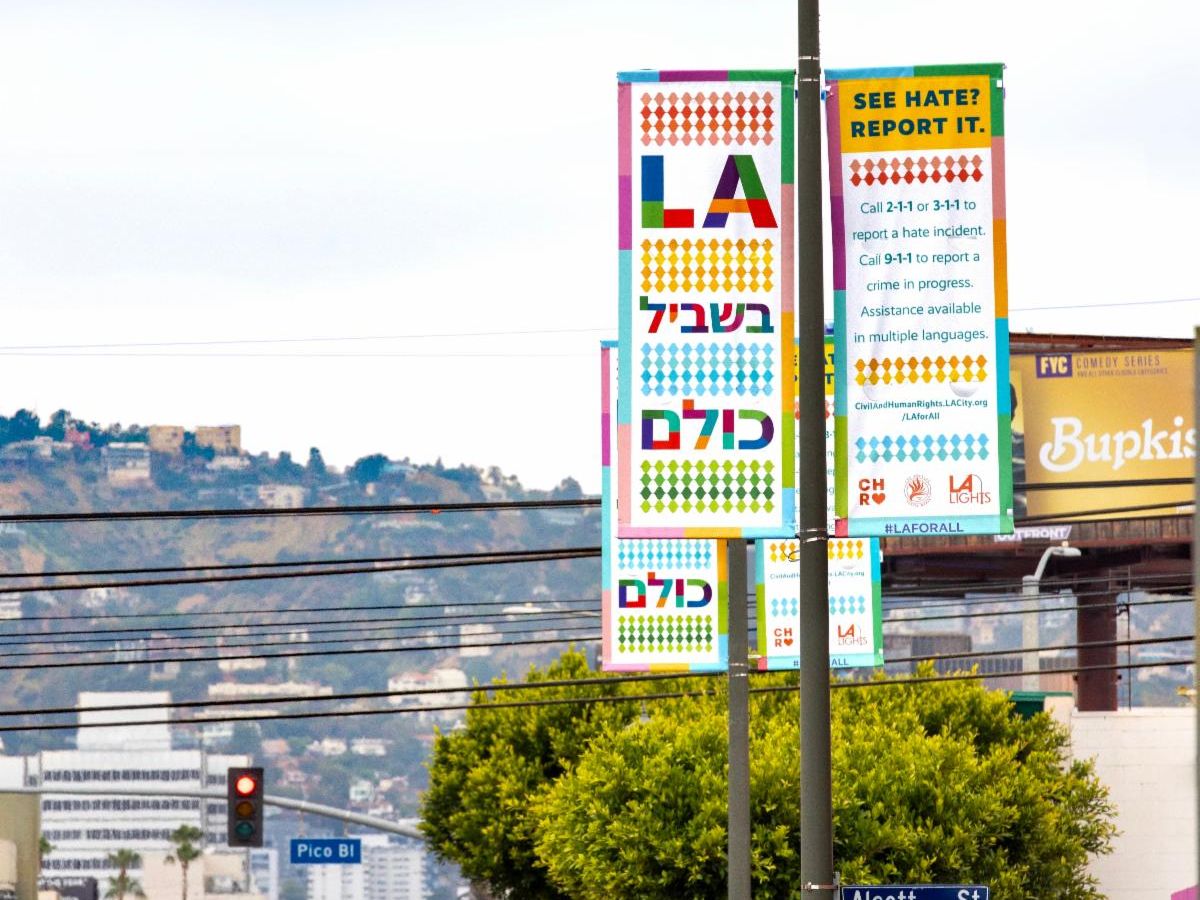 Colorful banners on street light poles say "LA IS FOR EVERYONE" in Hebrew and provide resources for reporting hate crimes.