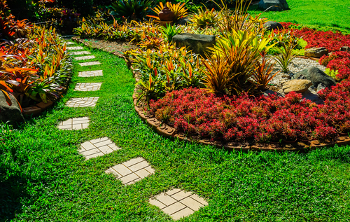 Garden landscape design with pathway intersecting bright green lawns and shrubs white sheet walkway in the garden. Landscape design with colorful shrubs. grass with bricks pathways. lawn care service.