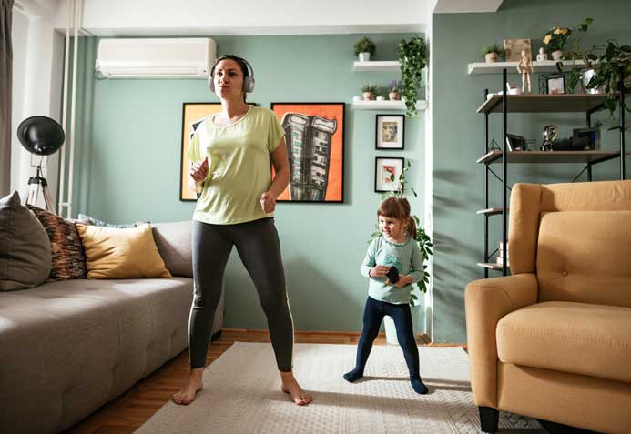 A mother and daughter working out side by side in their living room.
