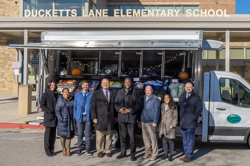 A group of people standing in front of the Roving Radish mobile truck.