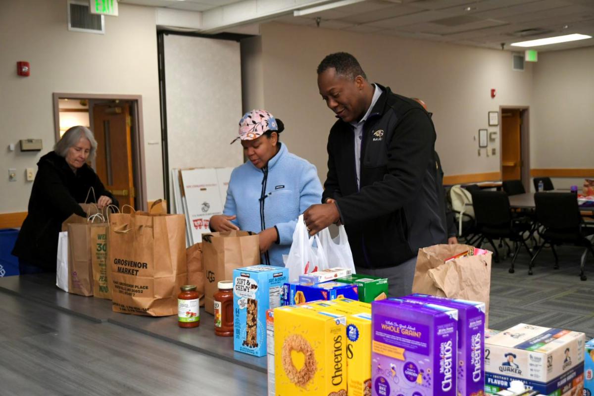Calvin Ball and a volunteer arranging food items standing behind a table