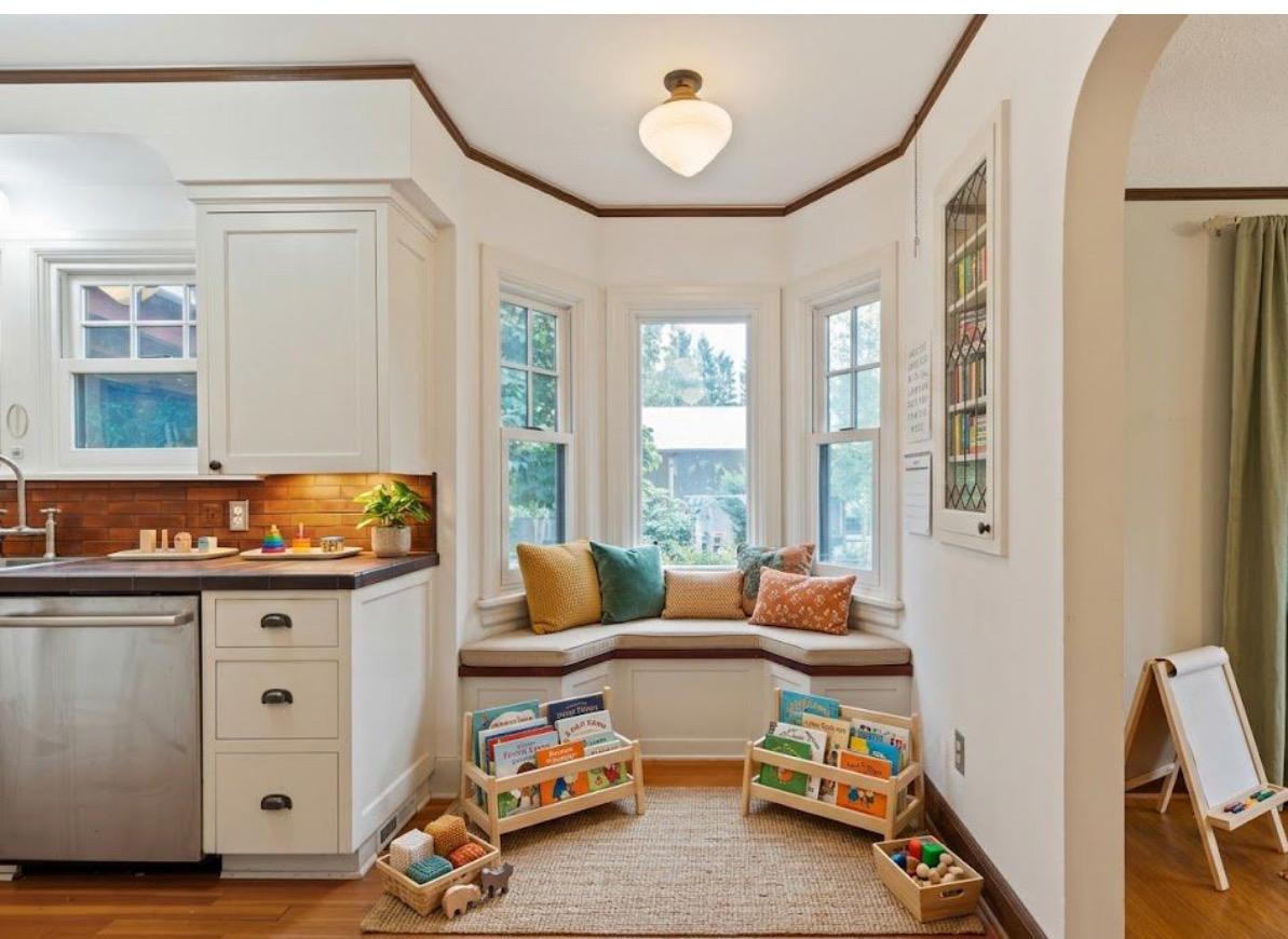 Home-based preschool features a window seating area / reading nook and book shelves full of childrens books
