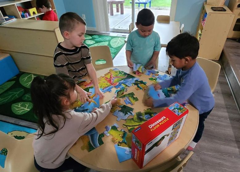 Four children gather around a table doing activities during preschool