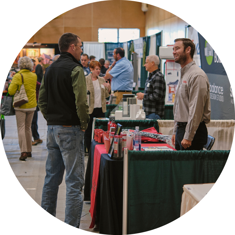 An exhibitor and attendee at the Green Home + Energy Show have a thoughtful and friendly conversation