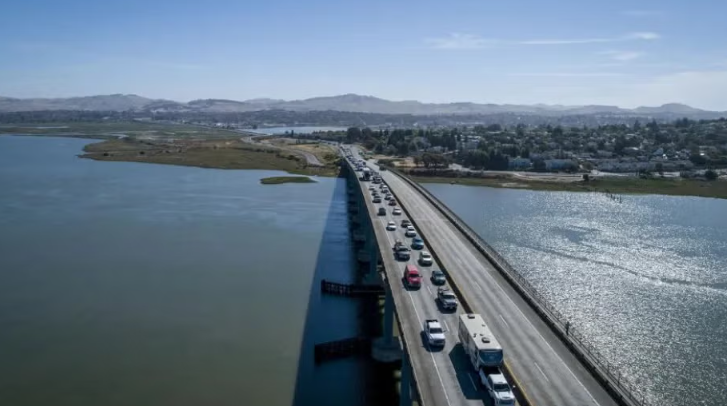 Photo is of a stretch of Highway 37 with cars travelling across a causeway over part of the bay. 