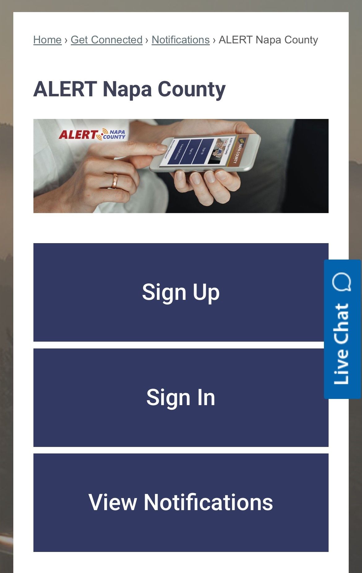Screenshot of the Alert Napa County Website with a header image of a person using a smart phone to go to the Alert Napa County website. Alert Napa County logo is overlayed in the top left of the image. Three large purple buttons with white text are in the center of the image. The options are sign up sign in and view notifications.