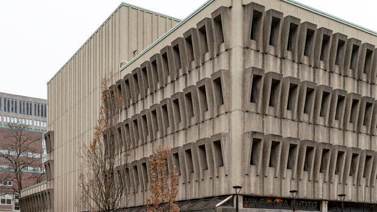 Detail of large multistorey concrete structure with corner view showing multiple covered windows on each floor.