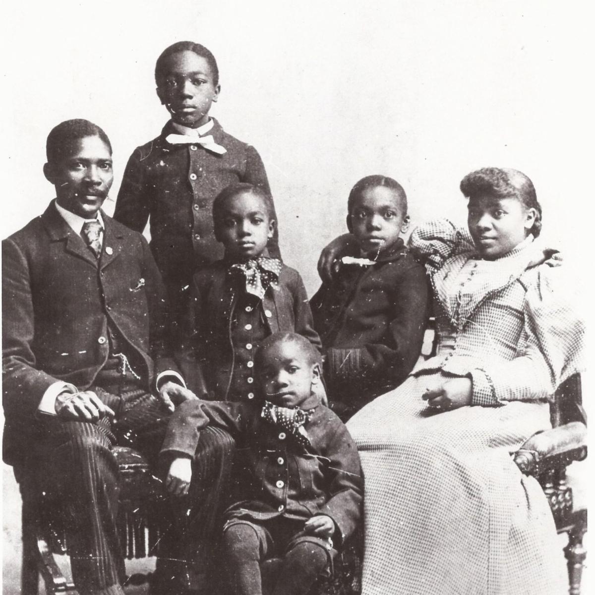 Black and white photograph of a family: husband, wife, and four young boys. All dressed in late 19th century clothing.
