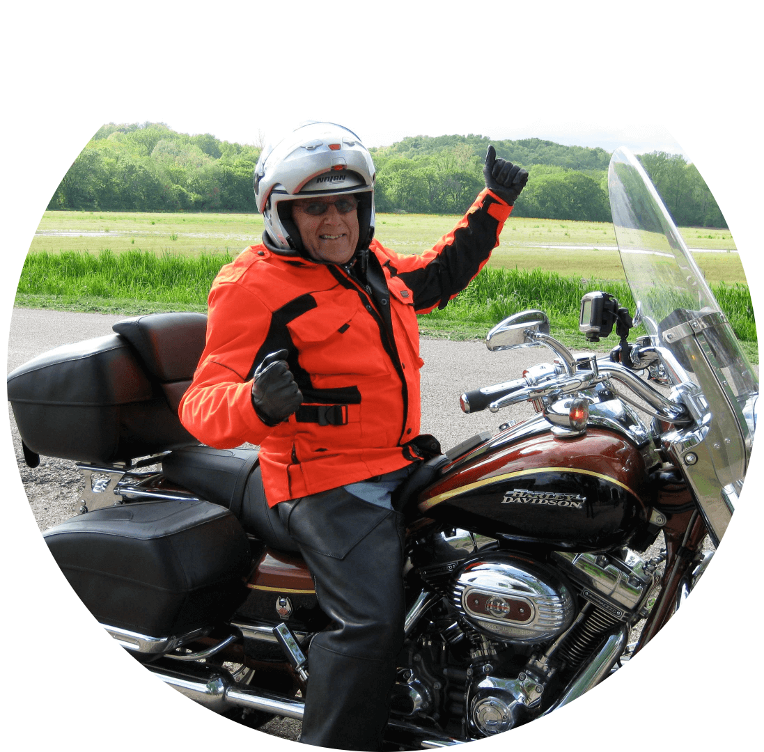 Harry Gaples, wearing sunglasses and a big smile while riding a motorcycle.