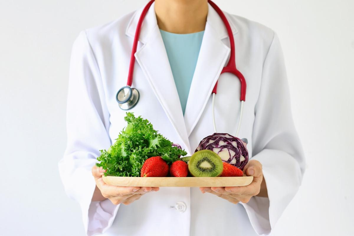 Cardiologist holding a tray of colorful fruits and vegetables