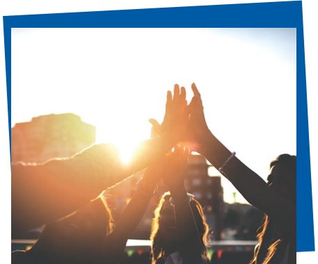 Four people unite hands with the sunlight behind them. 