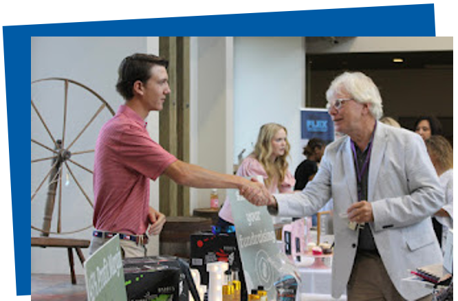 A student entrepreneur meets with a person reviewing his business. 