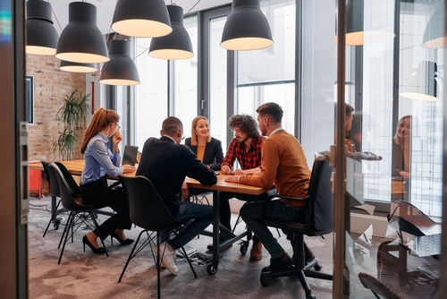 In a sleek glass office space_ a team of business professionals engage in lively discussions and exchange strategic ideas_ showcasing collaboration and innovation at the heart of modern corporate