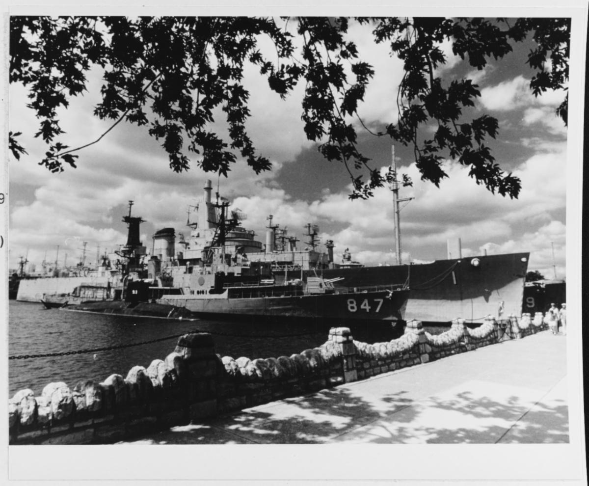 three naval vessels moored next to each other with a walkway in foreground