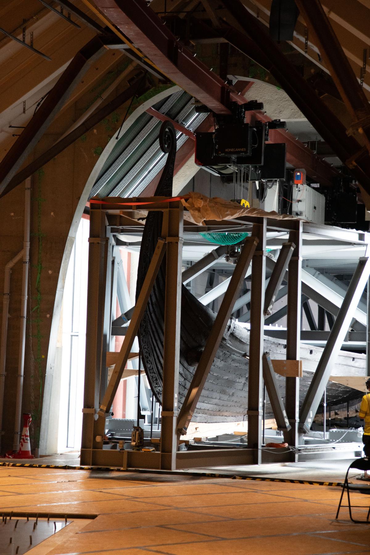 Viking ship in protective crate suspended by crane on track