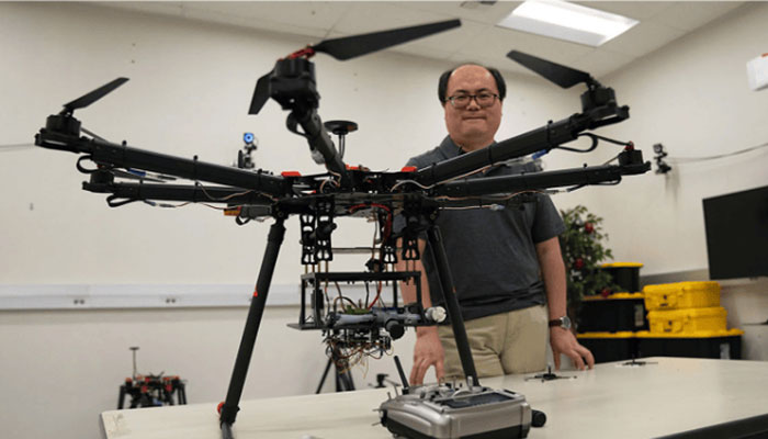 Professor Zhaodan Kong stands in front of large drone used to detect wildfires