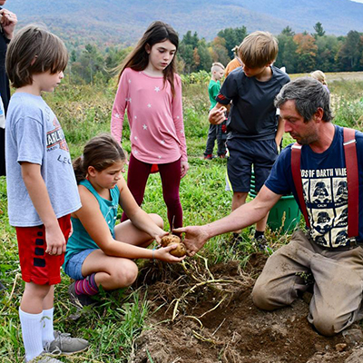 Farmer harvests crops with young children. Photo via NOFA-VT.