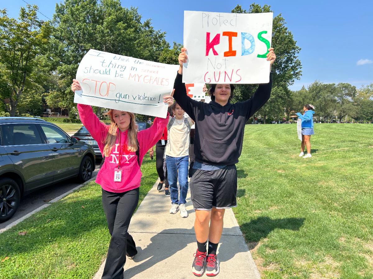 Students hold up their signs on gun violence while they march around the Oval for a walkout.