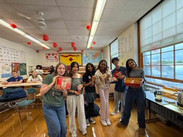 Students pose holding mooncakes and other treats to celebrate the Moon Festival.