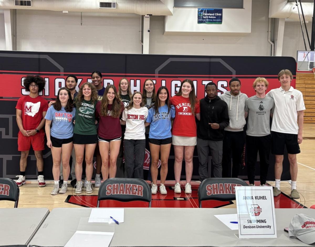 A group of senior athletes pose in the North Gym at SHHS wearing T-shirts from the colleges where they will continue their athletic careers.