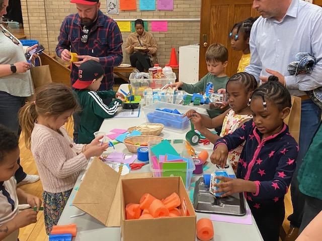 Preschool children play with activities on a tabletop.
