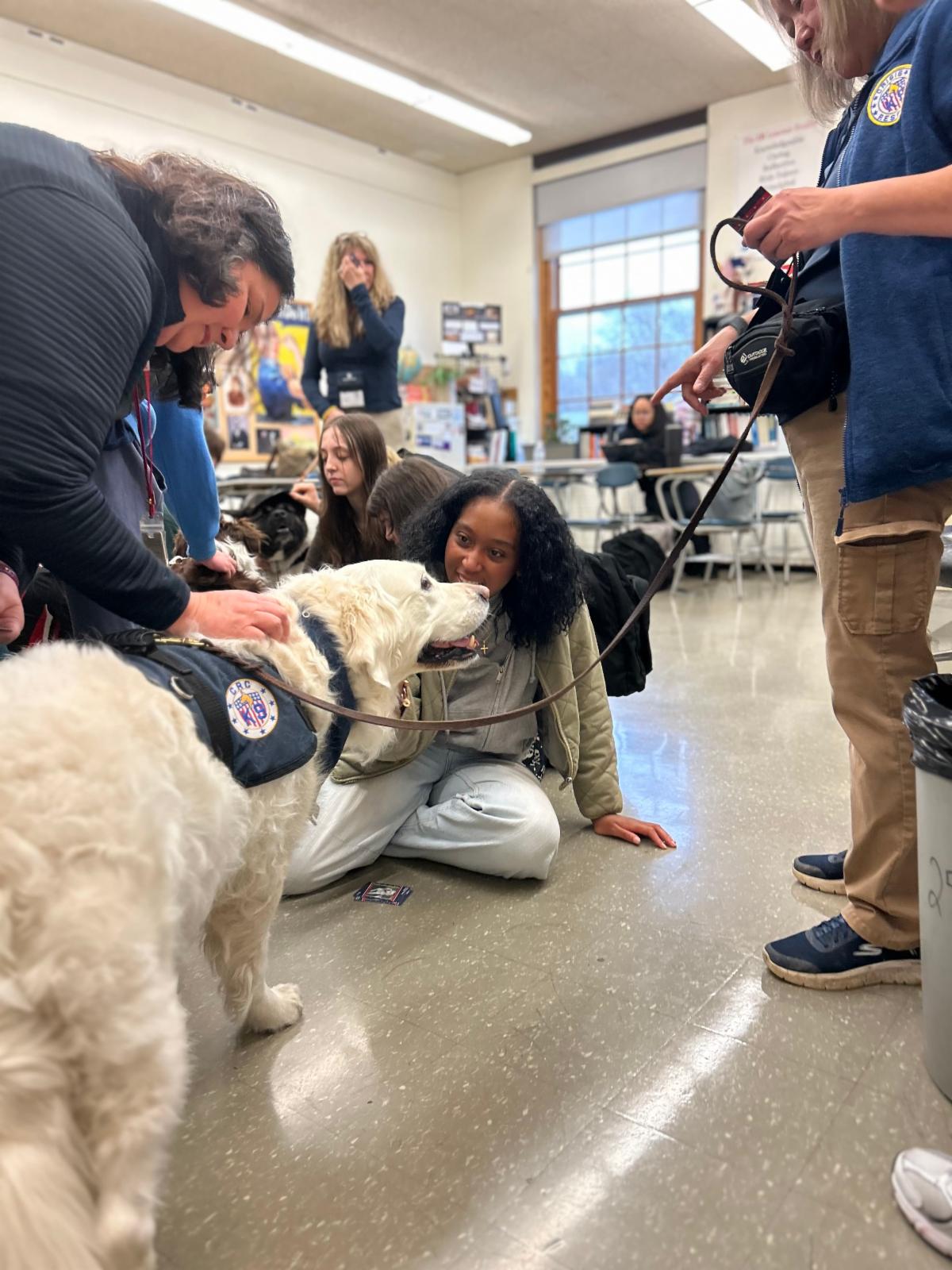 A students sits on the floor and pets a therapy dog at Shaker Heights High School.