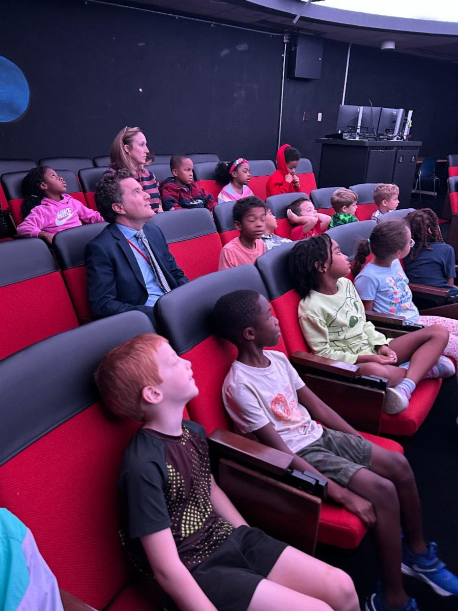 This photo shows students and the superintendent sitting in the planetarium.