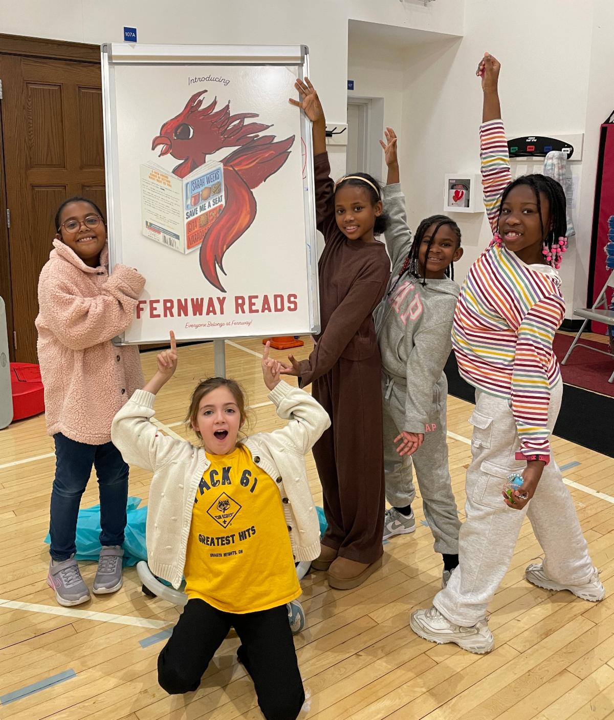 Fernway students pose and point to a sign that says Fernway Reads.