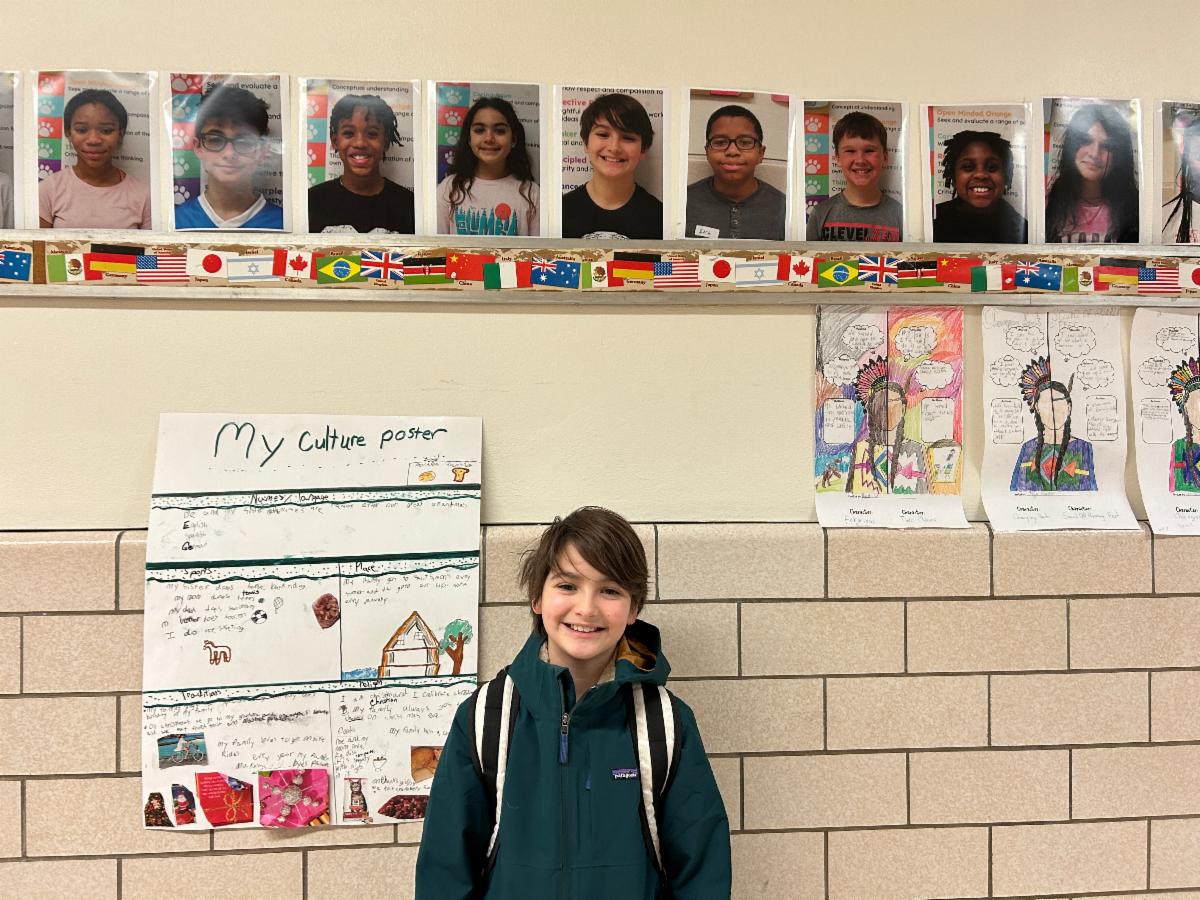 A Mercer student stands below his photo on the wall.
