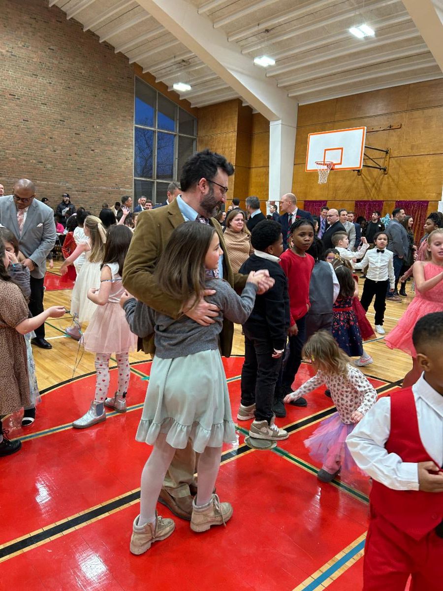 A dad and daughter dance together in the gym at the Middle School for a Sweetheart dance on Valentine's Day.