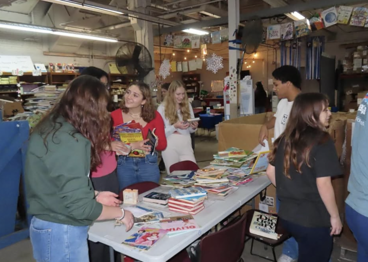 Members and friends of the Latin Club sort books on a table at the Cleveland Kids Book Bank.